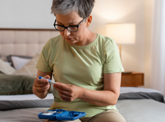 Elderly woman with dementia checking her glucose level, highlighting the importance of GLP-1 agonists in reducing dementia risk for type 2 diabetes patients.