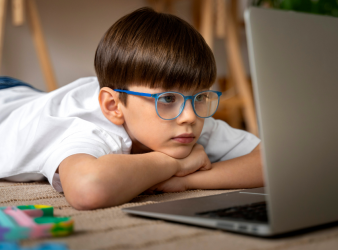 A child using a computer with a worried expression, representing the link between screen time and myopia.